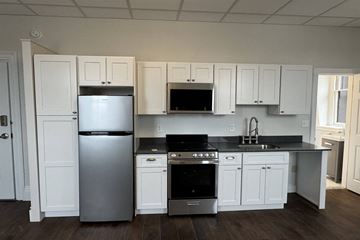Portsmouth apartment for rent - A kitchen with white cabinets and black countertops.
