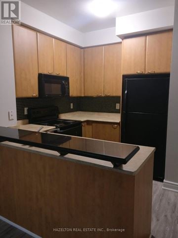 Mississauga (City Centre) condo for rent - A kitchen with wooden cabinets and black appliances.