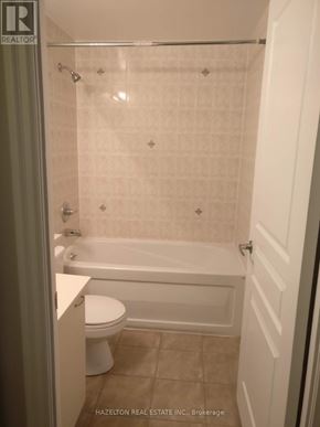 Mississauga (City Centre) condo for rent - A white toilet sits next to a bathtub in a bathroom.