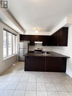 Whitby (Port Whitby) townhouse for rent - A kitchen with brown cabinets and a white fridge.