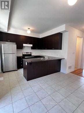 Whitby (Port Whitby) townhouse for rent - A kitchen with a refrigerator, stove, and sink.