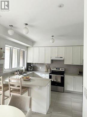 Whitby (Port Whitby) townhouse for rent - A white kitchen with a table and chairs.