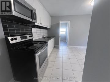 Toronto (Caledonia-Fairbank) apartment for rent - A kitchen with a black stove top oven and white cabinets.
