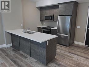 Windsor condo for rent - A kitchen with a refrigerator, microwave, and oven.