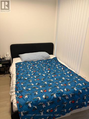 Toronto (Waterfront Communities) condo for rent - A bed with a blue dinosaur print sheet is in a room with a white wall.