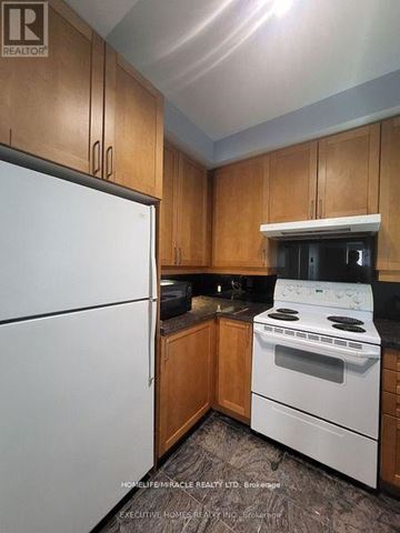 Toronto (Church-Yonge Corridor) condo for rent - A kitchen with wooden cabinets and a white fridge.