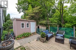 Owen Sound apartment for rent - A small pink shed sits in a backyard with a wooden deck and patio furniture.