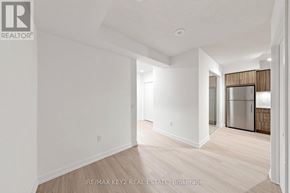 Toronto (Humber Heights) condo for rent - A white room with a wooden floor and a door leading to a kitchen.