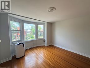 Hamilton apartment for rent - A room with wooden floors and a window overlooking a residential area.