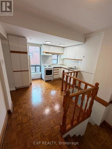 Toronto (Runnymede-Bloor West Village) apartment for rent - A kitchen with white cabinets and a wooden staircase.