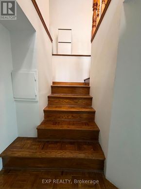 Toronto (Runnymede-Bloor West Village) apartment for rent - A set of wooden stairs with a white wall and a brown wooden handrail.