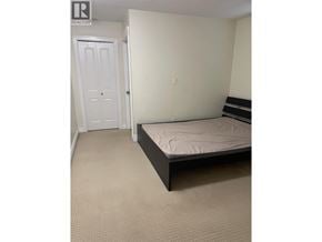 Burnaby apartment for rent - A bedroom with a bed, carpeted floor, and a door.