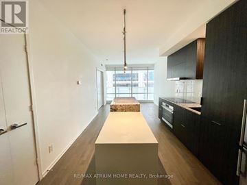 Toronto (Church-Yonge Corridor) condo for rent - A spacious kitchen with black cabinets and a white island.