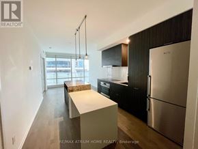 Toronto (Church-Yonge Corridor) condo for rent - A modern kitchen with a refrigerator, cabinets, and a dining table.