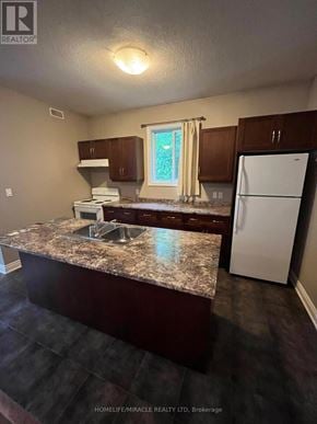Kitchener apartment for rent - A kitchen with a granite counter top and a white refrigerator.