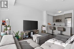 Hamilton (Lakeshore) condo for rent - A modern living room with a grey sofa set and a flat screen TV.