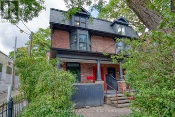 Toronto (Cabbagetown-South St. James Town) apartment for rent - A house with a red door and a balcony is surrounded by greenery.