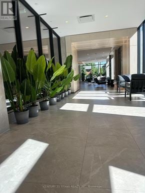 Toronto (Bayview Village) condo for rent - A lobby with a row of potted plants on the left and a row of chairs on the right.