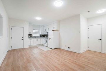 Surrey apartment for rent - A kitchen with white cabinets and a wooden floor.