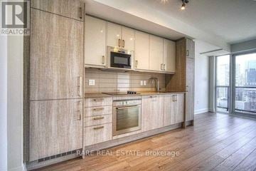 Toronto (Church-Yonge Corridor) condo for rent - A modern kitchen with wooden cabinets and a stainless steel oven.