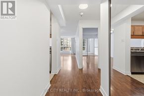 Toronto (Church-Yonge Corridor) condo for rent - A real estate company logo is displayed on a wall in a spacious, well-lit room with hardwood floors and white walls.