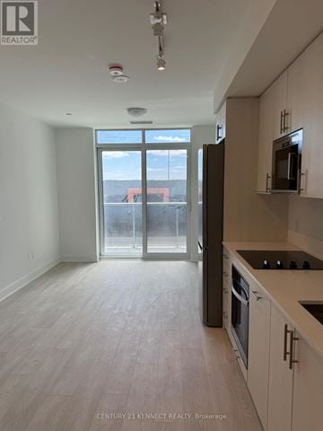 Oshawa (Windfields) condo for rent - A kitchen with white cabinets and a microwave above the stove.