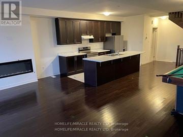 Brampton (Northwest Brampton) townhouse for rent - A kitchen with dark wood cabinets and a pool table.