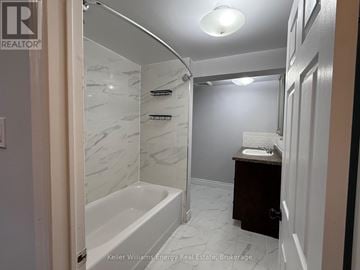 Oshawa (Donevan) apartment for rent - A bathroom with a marble tiled shower and a white bathtub.