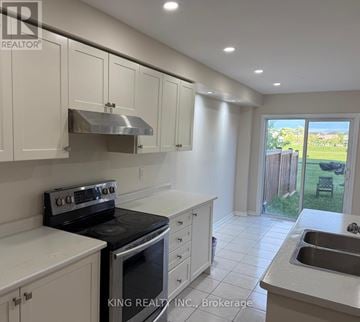 Brantford townhouse for rent - A kitchen with white cabinets and a stove top oven.