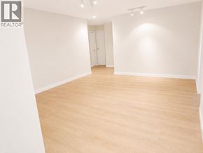 Burnaby apartment for rent - A large empty room with wooden flooring and white walls.