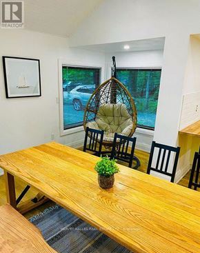 Innisfil apartment for rent - A wooden table with a plant and a hanging chair in a room.