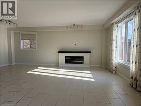 Waterloo apartment for rent - A large, empty room with a fireplace and a window letting in sunlight.