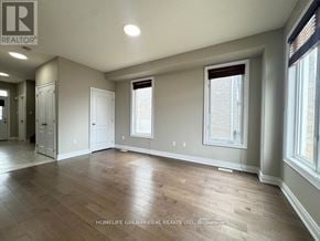 Barrie (Painswick South) apartment for rent - A spacious room with wooden flooring and a large window.