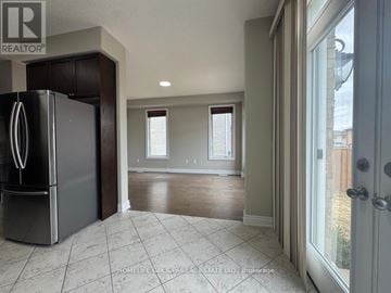 Barrie (Painswick South) apartment for rent - A black refrigerator is in a kitchen with tile flooring and a doorway leading to another room.