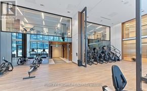 Toronto (Newtonbrook East) condo for rent - A gym with a row of exercise bikes and a row of exercise machines.