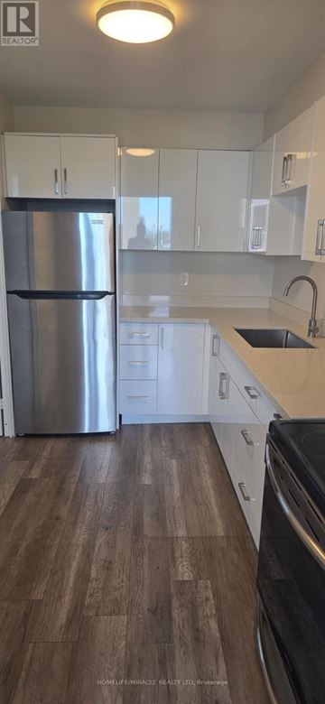 Toronto (Crescent Town) condo for rent - A kitchen with a stainless steel refrigerator and wooden flooring.
