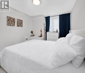 Ottawa condo for rent - A bedroom with a white bed and a window with blue curtains.
