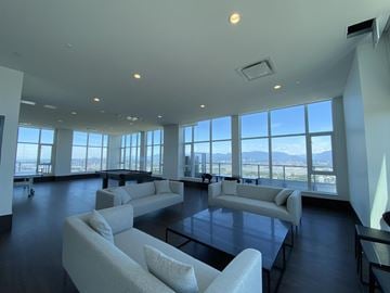 Surrey apartment for rent - A spacious living room with white furniture and a view of the city.