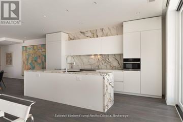 Huntsville (Chaffey) condo for rent - A modern kitchen with white cabinets and a marble island.
