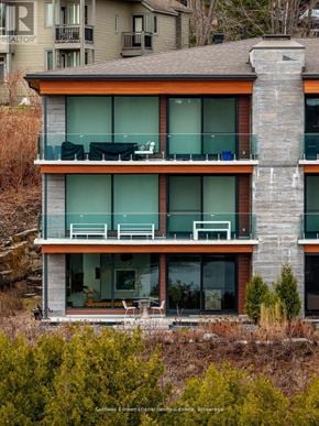 Huntsville (Chaffey) condo for rent - A modern two-story house with a balcony and a stone chimney.