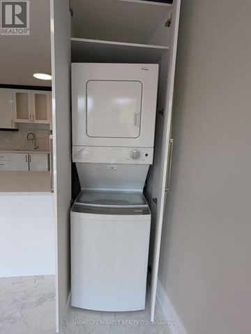 Toronto (Oakwood Village) apartment for rent - A white dishwasher is in a kitchen with a brokerage logo on the wall.