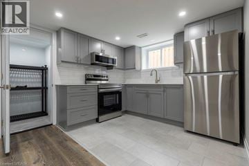 Hamilton apartment for rent - A modern kitchen with a refrigerator on the right and a microwave above the oven.