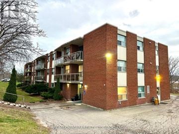 St. Catharines (Glendale/Glenridge) condo for rent - A brick apartment building with a parking lot in front.