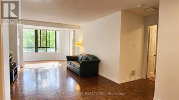 Toronto (Kensington-Chinatown) condo for rent - A living room with a black couch and a lamp.