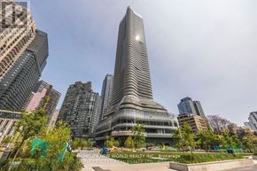 Toronto (Bay Street Corridor) condo for rent - A tall, modern building with a curved glass facade stands in the center of a cityscape.