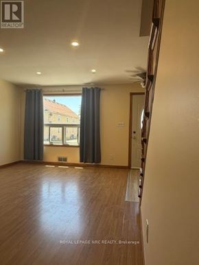 Welland (Lincoln/Crowland) apartment for rent - A spacious room with wooden floors and a large window with curtains.