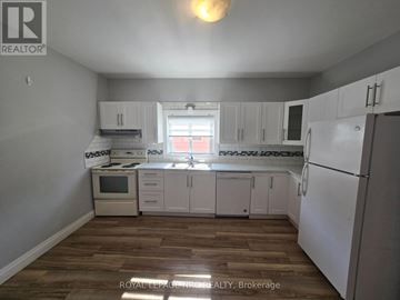 Fort Erie (Central) triplex for rent - A kitchen with white cabinets and a wooden floor.