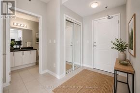 Oakville (Wm Westmount) condo for rent - A white hallway with a brown rug and a plant on a table.