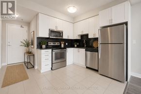 Oakville (Wm Westmount) condo for rent - A modern kitchen with white cabinets and stainless steel appliances.