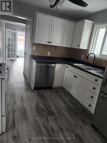 Niagara Falls (Clifton Hill) apartment for rent - A kitchen with white cabinets and a black countertop.